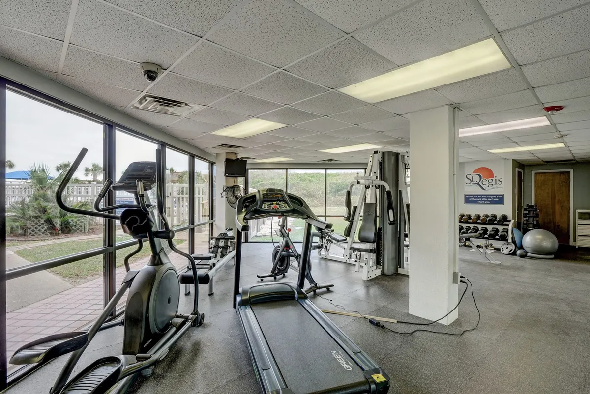 A bright and spacious fitness center filled with modern exercise equipment, including treadmills, ellipticals, strength training machines, and exercise balls. Large windows bring in natural light, creating an energizing space for guests to pursue wellness goals.