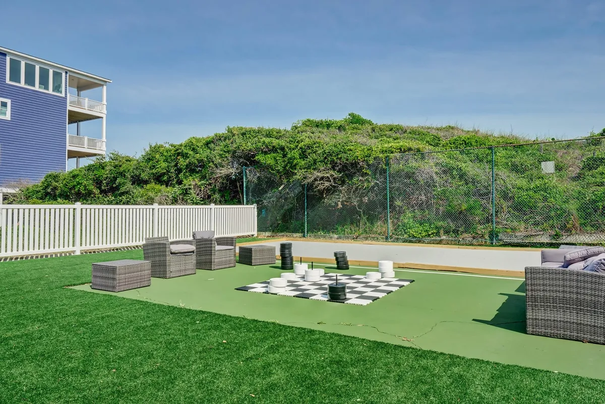 An inviting exterior scene displays a large outdoor chess set, comfortable seating, and abundant greenery, suggesting a casual and engaging atmosphere perfect for socializing, relaxation, and outdoor recreation.