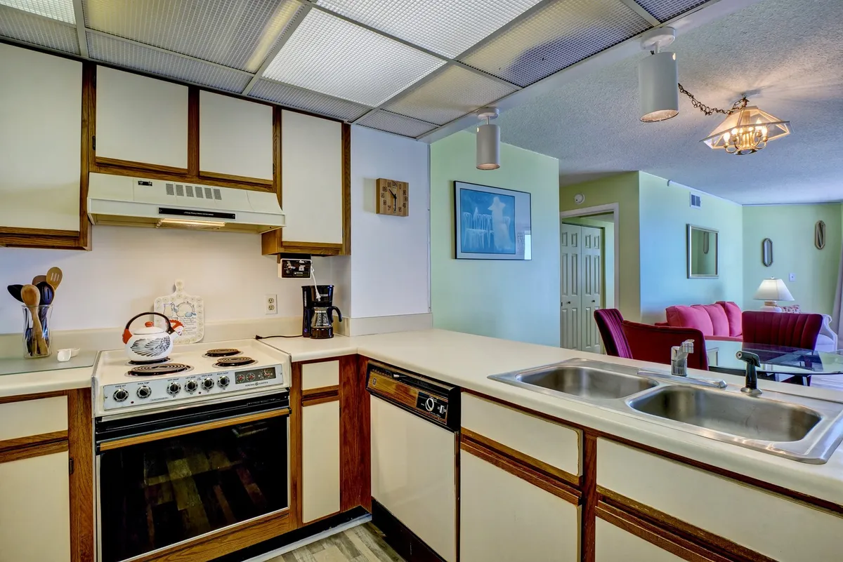 A closer look at the kitchen reveals a homey space with a stove, sink, cabinets, coffee maker, and kettle. The setup invites guests to easily prepare anything from quick breakfasts to more elaborate meals, embodying both vintage charm and modern convenience.