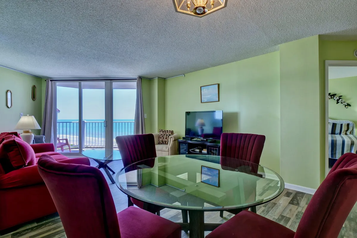 An open-plan space featuring a dining table for four, a comfortable seating area, large windows overlooking the Atlantic, and a television. The space is casual and welcoming, with the dining area and living space flowing together to maximize social interaction and enjoyment of the view.