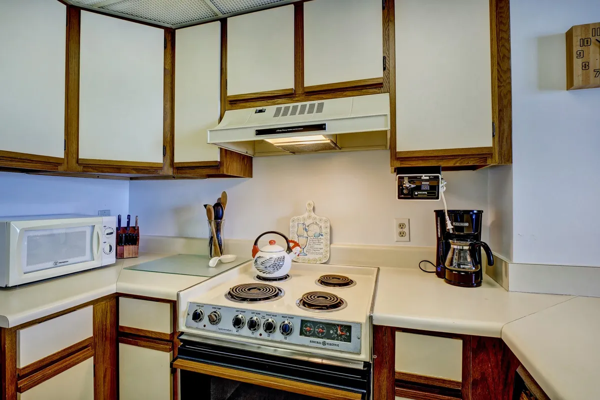The image shows a well-stocked kitchen area with a stove, sink, microwave, coffee maker, and an array of kitchen utensils. The layout is functional and encourages cooking and gathering, perfect for family meals or relaxed breakfasts.